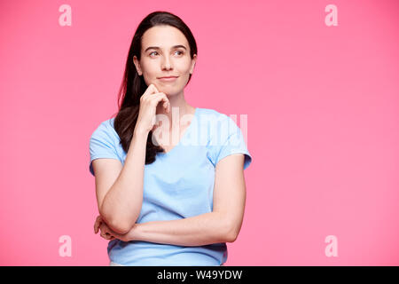 Giovani serena brunette femmina su sfondo rosa cercando riposo Foto Stock