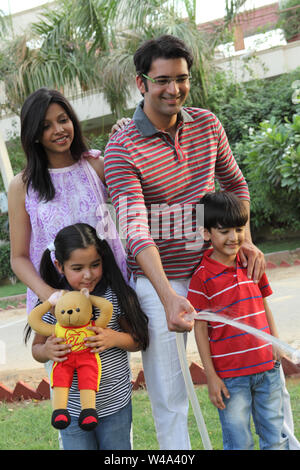 Family watering garden with hose and smiling Stock Photo