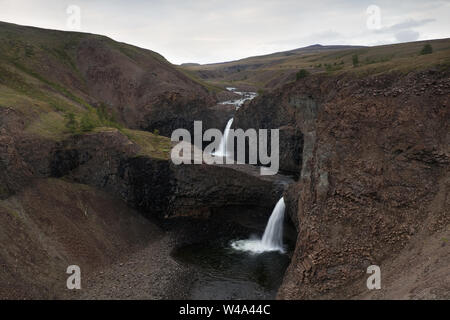 Il fiume Kugen, la maestosa cascata che si tuffa nel Rugged Canyon circondato dalle montagne nell'altopiano di Putorana, a nord della Russia, riserva naturale di Putoranskiy. Foto Stock