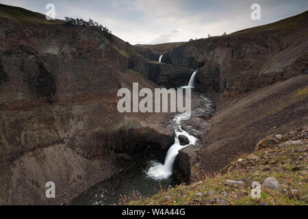 Il fiume Kugen, la maestosa cascata che si tuffa nel Rugged Canyon circondato dalle montagne nell'altopiano di Putorana, a nord della Russia, riserva naturale di Putoranskiy. Foto Stock