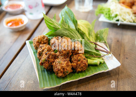 Asian croccante cucina Tailandese chiamata 'Larb Thod' interno con erbe e grigliate di carne di maiale in palla. Servire con verdura Foto Stock
