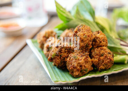 Asian croccante cucina Tailandese chiamata 'Larb Thod' interno con erbe e grigliate di carne di maiale in palla. Foto Stock