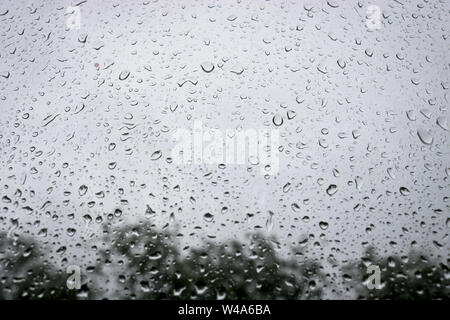 Grandi gocce di acqua sul vetro. Le gocce di pioggia sul parabrezza di un auto contro lo sfondo del cielo cielo. Foto Stock