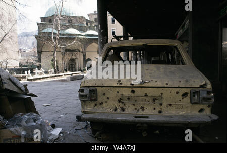 Xxi Aprile 1993 durante l'assedio di Sarajevo: una vettura riddled con mortaio bomb shrapnel 'parcheggiato in un arcade su Vase Miskina (oggi chiamato Ferhadija Street). In fondo è la moschea Ferhadija. Foto Stock