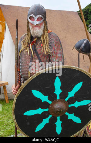 Età vichinga, costumi di abbigliamento e armi a Heysham, Lancashire. Luglio, 2019. Le bandiere di battaglia volano alla baia di Morecambe mentre 70 re-enactors del guerriero di eredità storica si riuniscono ad un'accampamento di storia vivente medievale per dimostrare le armi dell'era e fanno la battaglia sul verde del villaggio. Gli dei Idin, Thor e Frey furono celebrati insieme ad altre mitologie vichinghe. Foto Stock