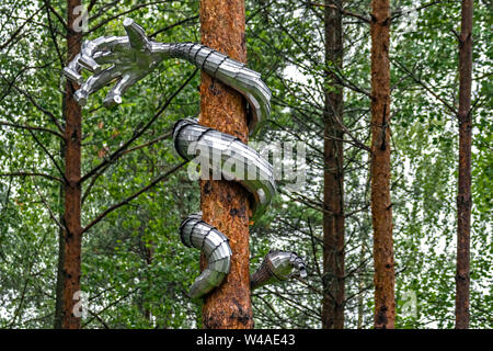 Il serpente è realizzato nella forma di una mano di ferro, twining il tronco di un albero di pino. Foto Stock