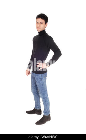 Una buona ricerca giovane uomo in nero maglione e jeans in piedi in studio, riposo e sorridente, isolato per sfondo bianco Foto Stock