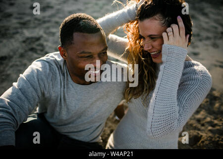 Multi razziale giovane ridere sulla spiaggia al tramonto Foto Stock