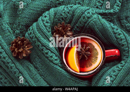 Natale e inverno tradizionale bevanda calda. Vin brulé in rosso la tazza con spice avvolto in un caldo verde maglione scandinavo. Foto Stock