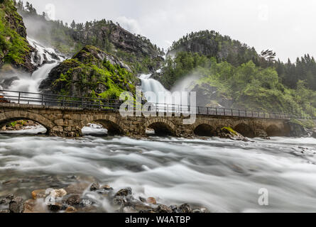 Twin Latefoss cascate ruscelli sotto il ponte di pietra agli archi, Odda, Hordaland county, Norvegia Foto Stock