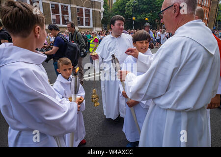 Londra, Regno Unito. Il 20 luglio 2019. La gente in attesa per il corteo storico nella zona londinese di Clerkenwell dalla Basilica di San Pietro la Chiesa italiana. La processione annuale in onore di Nostra Signora del Monte Carmelo ha avuto luogo ogni anno dal momento che è stato dato il permesso speciale nel 1883. Le statue dei Santi vengono portati fuori dalla chiesa e portati in giro per l'area lungo con sette galleggianti biblica e vari gruppi a piedi tra cui alcuni in abito biblica e nuovo communicants. Tre colombe sono stati rilasciati come clero unito la processione e furono seguiti dai parrocchiani. Peter Marshall / Alamy Live News Foto Stock