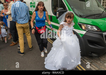 Londra, Regno Unito. Il 20 luglio 2019. Una giovane ragazza in un abito bianco per la sua Prima Comunione fa il suo modo di prendere parte al corteo storico nella zona londinese di Clerkenwell dalla Basilica di San Pietro la Chiesa italiana, la processione annuale in onore di Nostra Signora del Monte Carmelo. Esso ha avuto luogo ogni anno dal momento che è stato dato il permesso speciale nel 1883. Le statue dei Santi vengono portati fuori dalla chiesa e portati in giro per l'area lungo con sette galleggianti biblica e vari gruppi a piedi tra cui alcuni in abito biblica e nuovo communicants. Tre colombe sono stati rilasciati come clero unito la processione e sono state follo Foto Stock