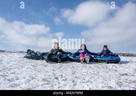 I fratelli sono schierate per sled discesa da una collina sorridente e felice Foto Stock