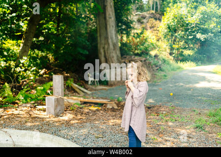 Vista laterale di una giovane ragazza di mangiare un s'more da un falò Foto Stock