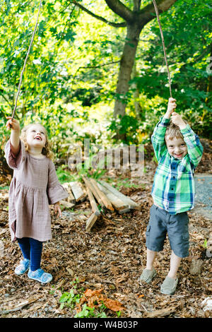 Dritto sul ritratto di una ragazza e un ragazzo giocando nella foresta Foto Stock