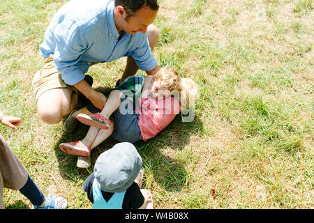 Vista da sopra di un papà e due bambini che giocano in erba Foto Stock