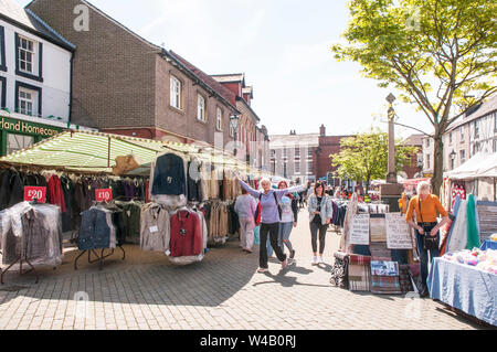Tre giovani donne godendo la giornata passeggiando per le bancarelle del mercato settimanale in piazza del mercato Poulton le Fylde Lancashire England Regno Unito Foto Stock
