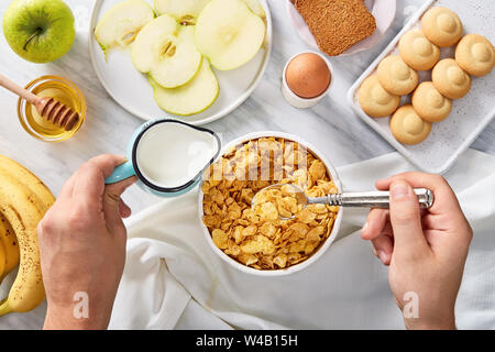 La prima colazione ricca di ingredienti. Versare il latte sul settore dei cereali. Vista superiore Foto Stock