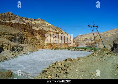 Le linee elettriche di alimentazione sulla strada per il borgo antico di Chuksang, visibile in background. Mustang Superiore regione, Nepal. Foto Stock