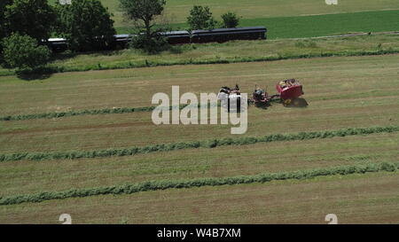 Vista aerea di un agricoltore Amish raccolto il suo raccolto con 4 cavalli e moderne attrezzature Foto Stock