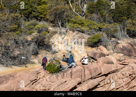 Turisti che si godono il pranzo sulle rocce al Baia Luna di Miele nel Parco Nazionale di Freycinet,Tasmania, Australia Foto Stock