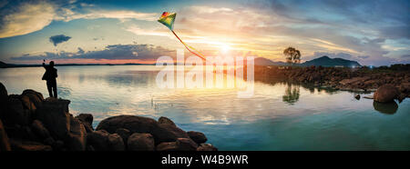 Imprenditore rilassante con un aquilone, tramonto a Gaborone dam, in Botswana dopo una breve pioggia Foto Stock
