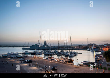 Cartolina da Ortigia. Yacht, barche, persone sul lungomare come il sole tramonta in una calda giornata estiva in Ortigia, Siracusa, Sicilia Foto Stock