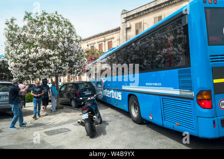 Un ingorgo di Noto, Sicilia. La Grande Gita in autobus non è in grado di completare un giro a sinistra su questa strada stretta a causa della alla rinfusa automobili parcheggiate. Buona natura Foto Stock