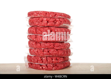 Pila di materie hamburger di polpette di carne su una tavola di legno con pezzi di carta pergamena tra gli hamburger per evitare che si attacchino. Isolato su whit Foto Stock