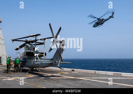 190719-N-NB544-1054 GOLFO ARABICO (19 luglio 2019) un AH-1Z Viper assegnato a mezzo marino Tiltrotor Squadron (VMM) 163 (rinforzato) vola a fianco del trasporto anfibio dock nave USS John P. Murtha (LPD 26) come Stati Uniti Marines assegnato a VMM 163 eseguire la pre-controlli di volo su un AH-1Z Viper durante le operazioni di volo. John P. Murtha è attualmente sulla sua prima implementazione e parte del Boxer anfibio gruppo pronto e la XI Marine Expeditionary Unit team ed è distribuito per la Quinta Flotta area di operazione a sostegno di operazioni navali per garantire maritime la stabilità e la sicurezza nella centrale Reg Foto Stock