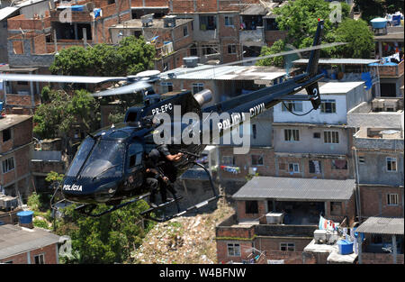 Elicottero della polizia civile di Rio de Janeiro, volando sopra la favela durante uno scontro tra la polizia e i trafficanti di droga in comunità a Rio de J Foto Stock