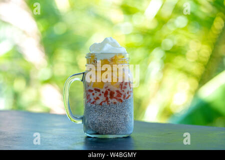 Latte di mandorle budino di Chia con fresche di mango giallo e rosso goji bacche in un vaso di vetro mug. Vegan materie prima colazione. Semi di Chia e freschi frutti tagliati e ber Foto Stock