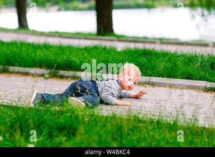 Bambino tentare di alzarsi dopo depositatisi in giù nel parco Foto Stock