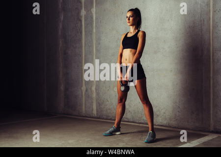 Giovane donna ottenere pronto per kettlebell swing. Allenamento a croce Foto Stock