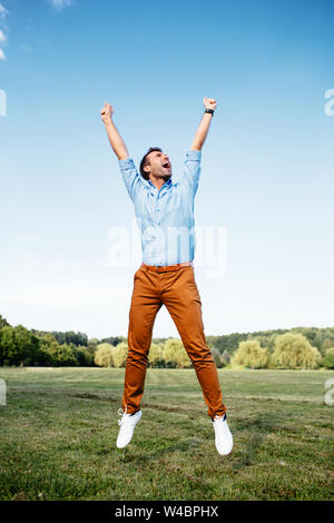 Foto di un uomo gioioso jumping vittoriosamente Foto Stock