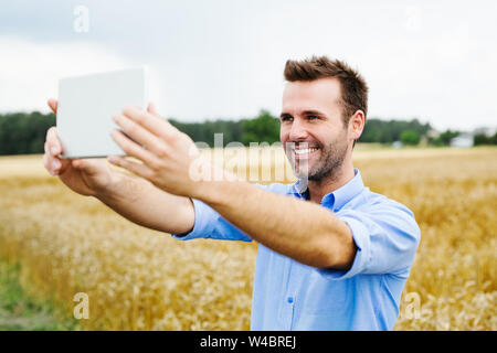 Uomo felice con tavoletta digitale in piedi in campo Foto Stock