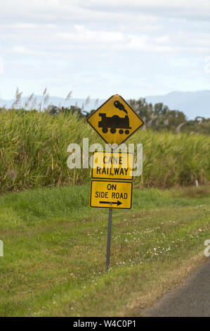 Un treno di zucchero attraversamento ferroviario segno accanto a una strada principale in campi di zucchero di canna nell'area di Mackay di Queensland in Australia. Mackay è il più grande p di zucchero Foto Stock