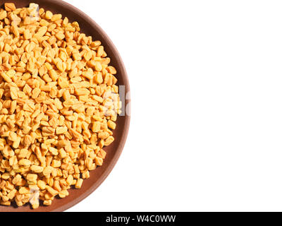 Spice Fieno greco (Trigonetla) su una argilla marrone piastra su uno sfondo bianco con spazio di copia Foto Stock