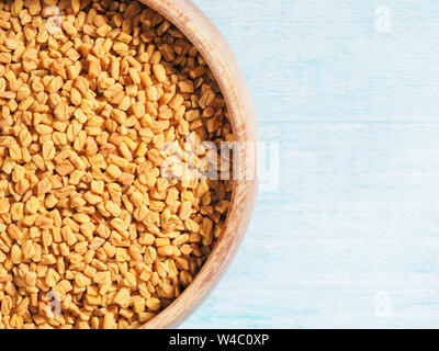 Spice Fieno greco (Trigonetla) in una coppa di legno su un blu e sfondo bianco Foto Stock