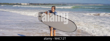 Surfer con la sua tavola da surf in esecuzione alle onde banner, formato lungo Foto Stock