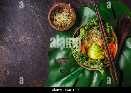 Vegano sano il pranzo in una ciotola di noce di cocco. Ciotola di Buddha su uno sfondo scuro. Foto Stock