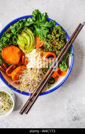 Vegano sano il pranzo in una ciotola bianco. Il Buddha ciotola con gli avocadi, patate dolci, germogli e verdure. Foto Stock