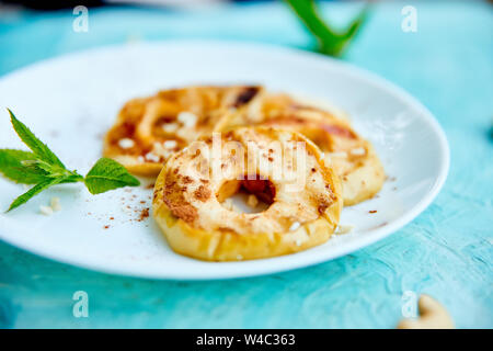 Grigliata di mele con cinamon sulla piastra bianca su sfondo blu. Grigliata di dessert. Barbecue di frutta. Copia dello spazio. Cibo sano. Cibo vegan. Foto Stock