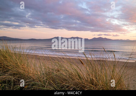 Tramonto sulla spiaggia di Newborough noto anche come Traeth Llanddwyn una lunga spiaggia sabbiosa di Anglesey cercando in tutta verso la penisola di Llŷn, Galles del Nord, Regno Unito Foto Stock