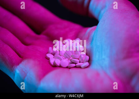 Bianco rotondo farmaco compresse pillole di heap della mano su sfondo nero Foto Stock