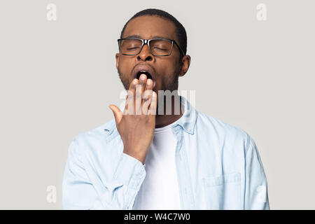 Stanco uomo nero sente assonnato coprono la bocca sbadigli Foto Stock