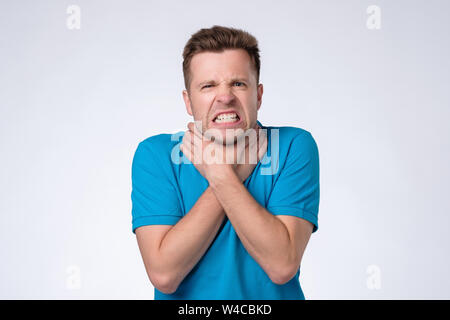 Uomo in camicia blu provare a uccidere se stesso, soffoca se stesso con entrambe le mani e soffocamento. Foto Stock