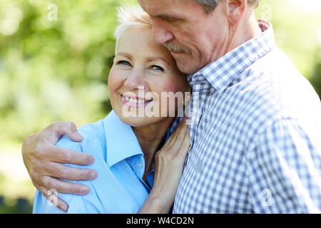 Vita ritratto di felice coppia senior abbracciare con amore mentre godendo passeggiata nel parco di estate Foto Stock