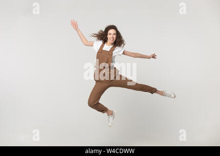 Felice donna attiva il salto in studio isolato su sfondo grigio Foto Stock