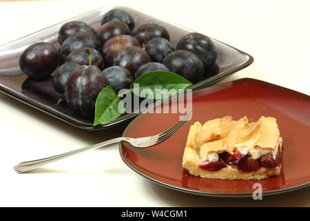 Torta di prugne e piatto con prugne fresche isolato Foto Stock